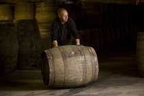 Worker rolling whisky cask in whisky distillery — Stock Photo