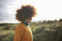 Frau mit Afrohaaren auf grasbewachsener Düne — Stockfoto