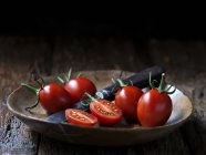 Tomates entières et coupées en deux lancashire jester et couteau dans un bol — Photo de stock