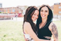 Portrait of tattooed young women in urban park — Stock Photo