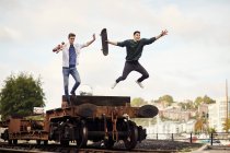 Two young men jumping from trailer on train track, Bristol, UK — Stock Photo