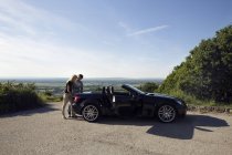 Pareja madura mirando el mapa en la bota del coche convertible - foto de stock