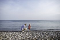 Mitte erwachsener Mann und Tochter beim Abschöpfen von Steinen am Ontariosee, Oshawa, Kanada — Stockfoto