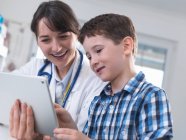 Médecin et garçon utilisant une tablette numérique — Photo de stock