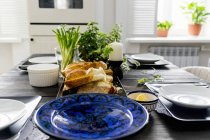 Ensemble table de cuisine avec tranches de pain, herbes fraîches et oignons de printemps — Photo de stock