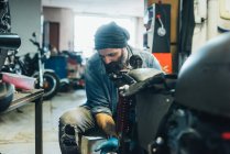 Зрілий чоловік, що працює на мотоциклі в гаражі — стокове фото