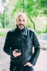Ritratto di motociclista maturo con smartphone in mano — Foto stock