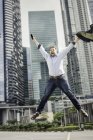 Щасливий бізнесмен стрибає з радістю біля міських хмарочосів будівель — стокове фото