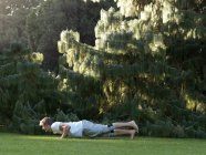 Jovem se exercitando ao ar livre, fazendo flexões — Fotografia de Stock