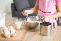 Young girl whisking ingredients together in bowl, mid section — Stock Photo