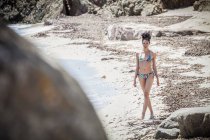 Молодая женщина в бикини стоит на пляже, Коста Рей, Сардиния, Италия — стоковое фото