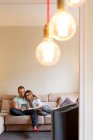 Mittleres erwachsenes Paar entspannt auf dem Sofa, schaut auf digitales Tablet — Stockfoto