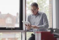 Homem usando tablet digital na janela do escritório — Fotografia de Stock