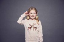 Portrait of young girl wearing Christmas jumper and bauble earrings — Stock Photo