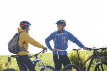 Cyclists holding bicycles chatting — Stock Photo