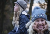 Portrait of girl and her sister in rural landscape wearing knit hat — Stock Photo