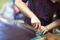 Trabalhador masculino na oficina de couro, usando ferramenta de corte para cortar couro, seção meados — Fotografia de Stock