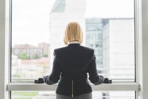 Вид спереду бізнес-леді, що дивиться з вікна офісу — стокове фото