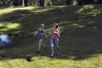 Dos amigas corriendo en el claro del bosque, Sattelbergalm, Tirol, Austria - foto de stock