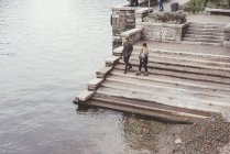Высокоугольный вид молодой пары, прогуливающейся по лестнице гавани, озеро Комо, Италия — стоковое фото