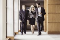 Empresários e mulher caminhando e conversando no corredor do escritório — Fotografia de Stock
