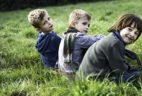 Retrato de tres chicos, sentados juntos en el campo, en otoño - foto de stock