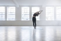 Задний вид женщины в танцевальной студии растяжения — стоковое фото