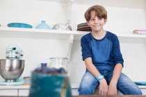 Junge sitzt auf Küchenarbeitsplatte — Stockfoto