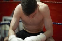 Boxer sentado no canto do ringue de boxe, exausto — Fotografia de Stock