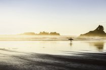 Male surfer carrying surfboard on Long Beach, Pacific Rim National Park, Vancouver Island, British Columbia, Canada — Stock Photo