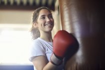Young female boxer punching punch bag in gym — Stock Photo
