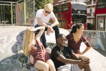Vier Freundinnen und Freunde sitzen im Skatepark der Stadt und unterhalten sich — Stockfoto