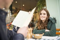 Casal no café pavimento olhando para o menu sorrindo — Fotografia de Stock