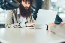 Young male hipster using laptop at desk — Stock Photo
