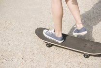 Pernas de skate feminino jovem na luz solar brilhante — Fotografia de Stock