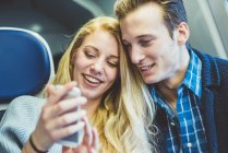 Молодая пара читает смс на смартфоне в вагоне поезда — стоковое фото