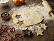 Table with christmas star biscuit dough and rolling pin — Stock Photo