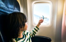 Boy playing with toy airplane at airplane window — Stock Photo