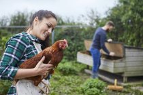 Jovem casal em galinheiro segurando frango — Fotografia de Stock