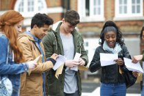 Jovens estudantes universitários adultos leitura resultados do exame no campus — Fotografia de Stock