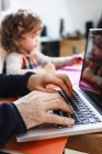 Close up of male hands typing on laptop and daughter drawing at table — Stock Photo