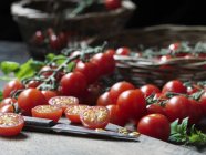 Tomates piccolini royale recién cortados a la mitad y cuchillo - foto de stock