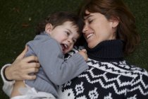 Ragazza sdraiata sul petto delle madri sorridente — Foto stock