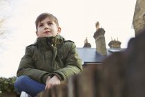Portrait of boy sitting looking out from wall — Stock Photo
