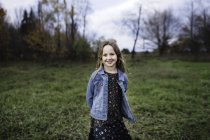 Chica joven sonriendo en el campo en chaqueta de mezclilla, Lakefield, Ontario, Canadá - foto de stock
