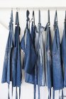 Row of denim aprons hanging on white wall — Stock Photo