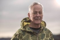Homme portant un manteau de camouflage à capuche imperméable regardant la caméra — Photo de stock