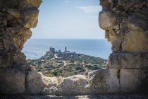 Veduta del faro attraverso un foro nel muro di pietra, Cagliari, Masua, Sardegna — Foto stock