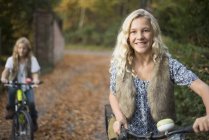 Portrait of two sisters cycling in autumn park — Stock Photo