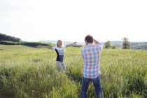 Мужчина фотографирует женщину в поле — стоковое фото